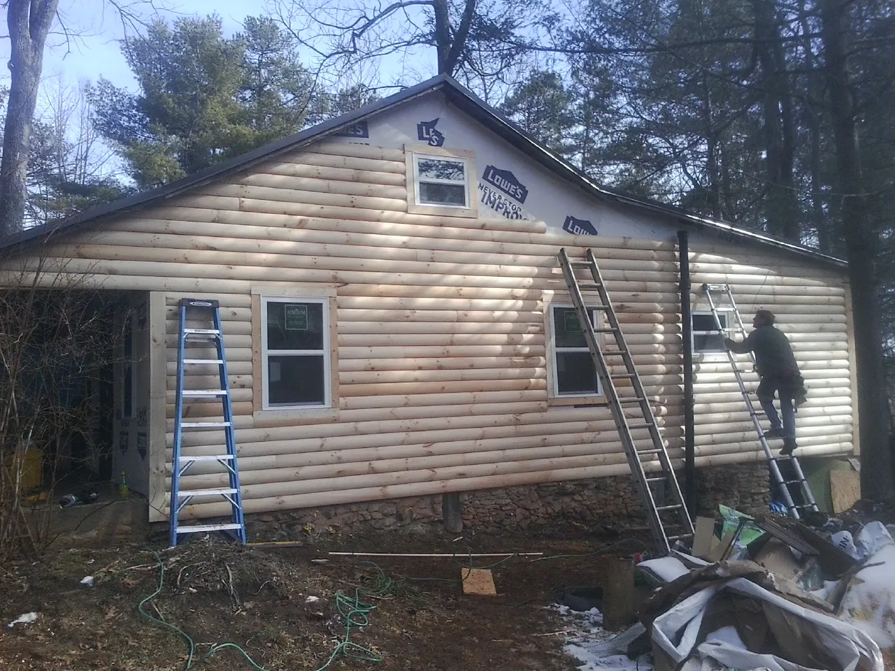 Ladders set against fresh log siding during an exterior remodel in Chinquapin