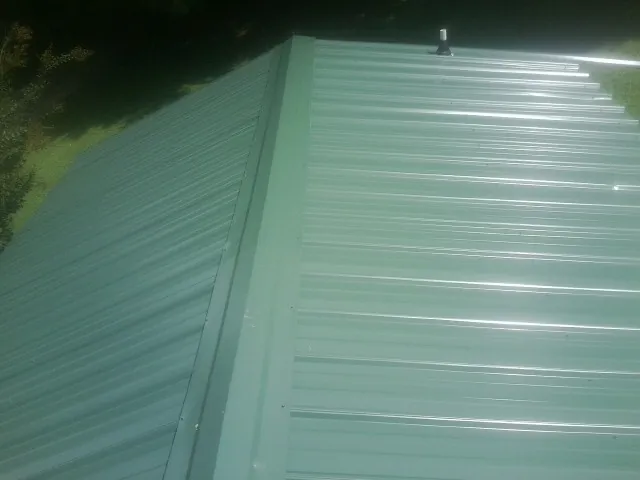 New green metal panels meeting at the ridge of a roof — Flat Roof Repair work by our crew in Chinquapin