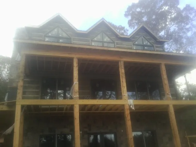 Dormers and porch framing on a large log home under construction — Roof Coating work by our crew in Chinquapin