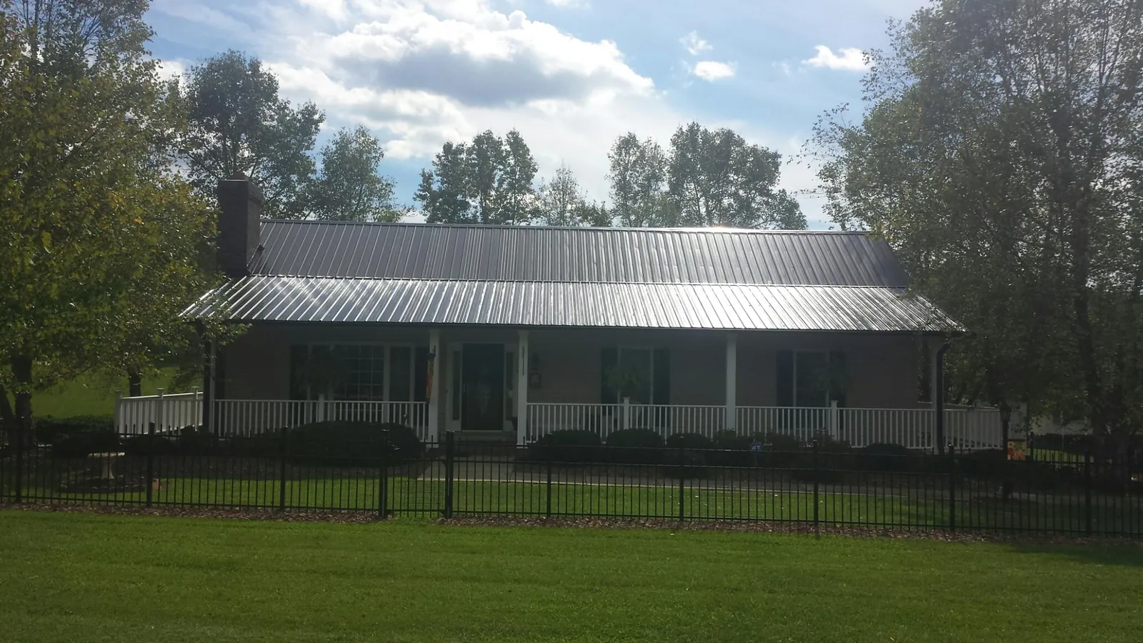 Gray metal roof on a brick ranch with a full width front porch — Gutter Guard Installation work by our crew in Chinquapin