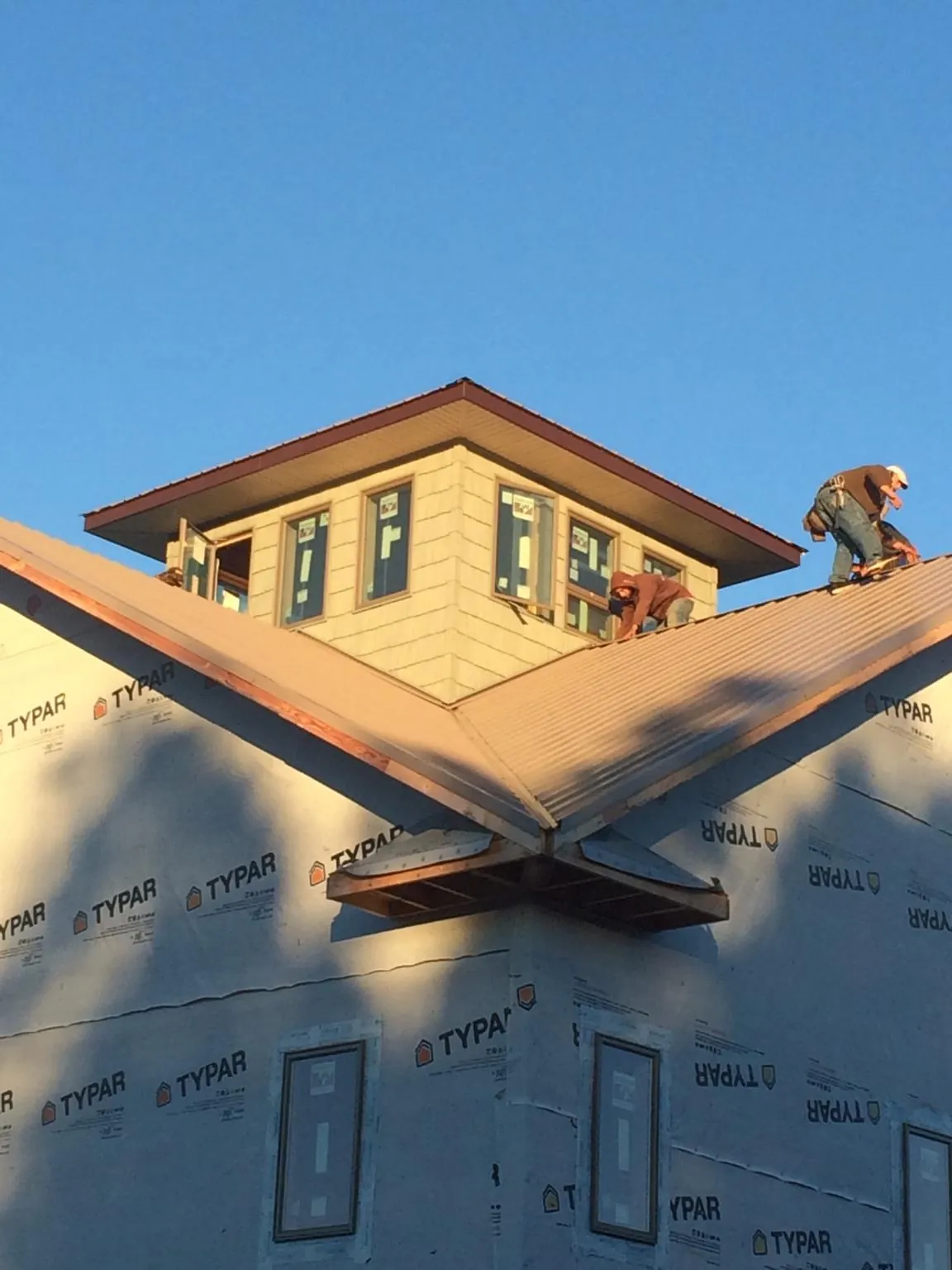 Roofers working around a rooftop cupola on a new metal roof at sunset — Roof Waterproofing in Chinquapin by Roofing Brothers